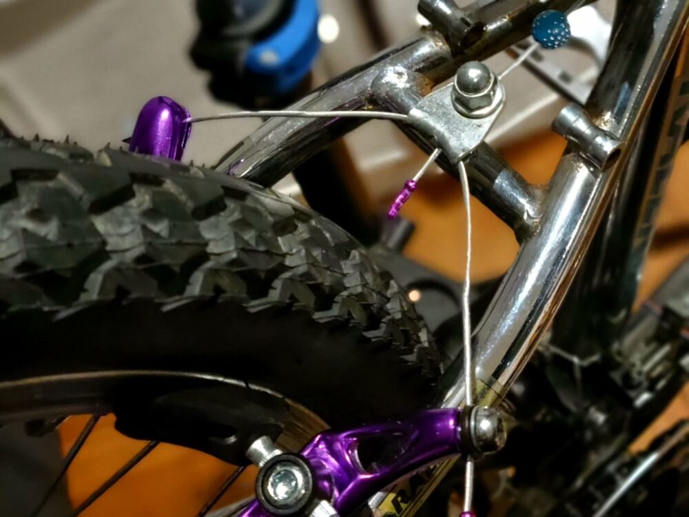 Frein cantilever arrière anodisé violet avec une perle bleu sur le câble